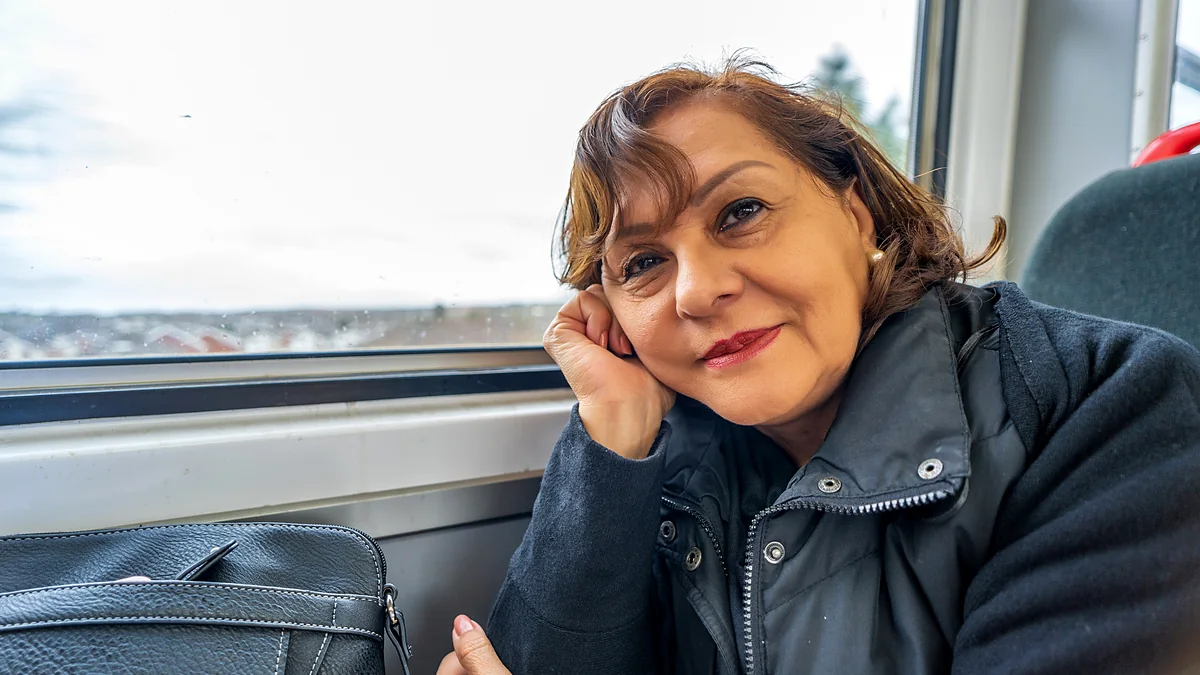Mujer mayor sentada junto a la ventana de un tren